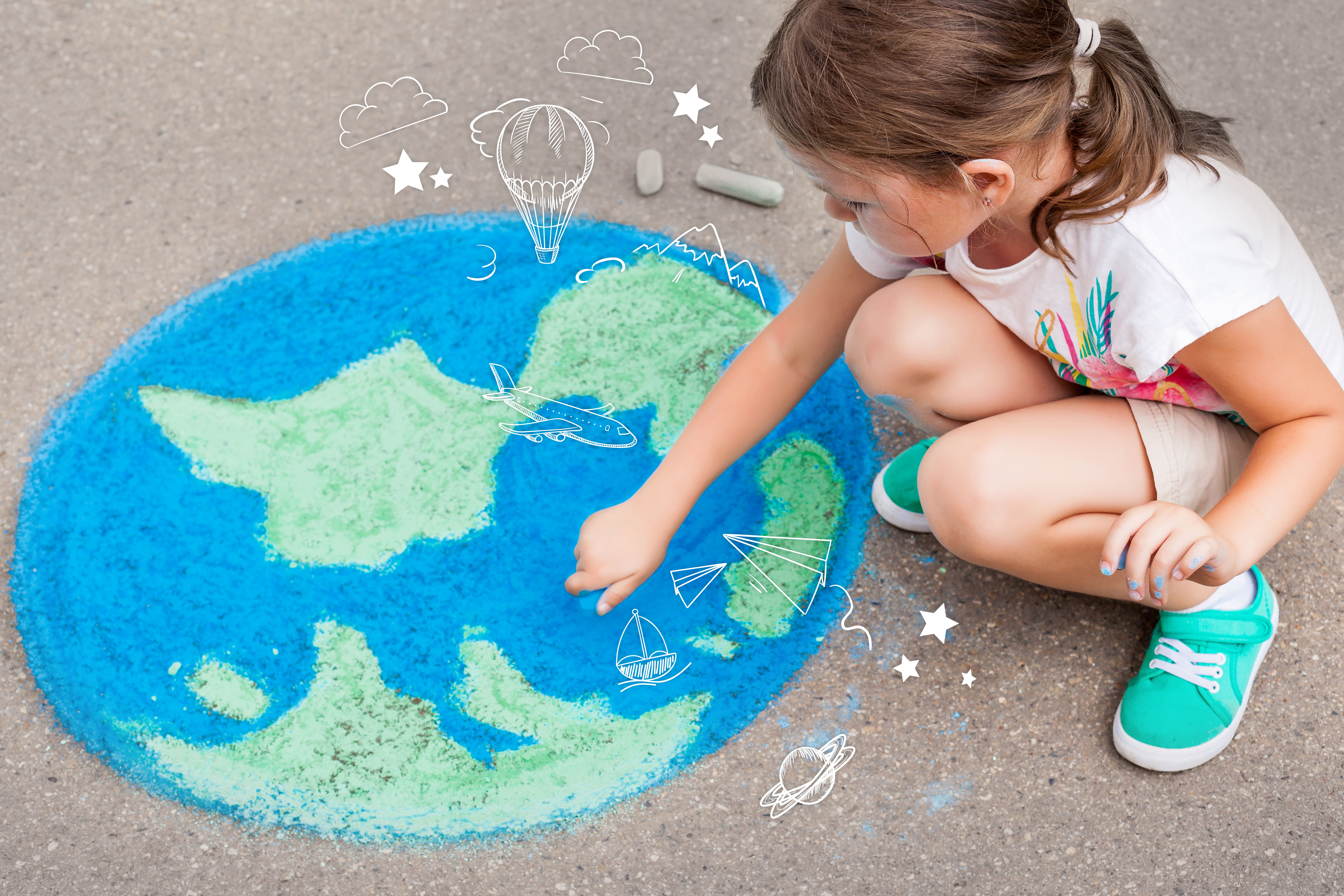 Bambina che colora un globo per terra con i gessetti