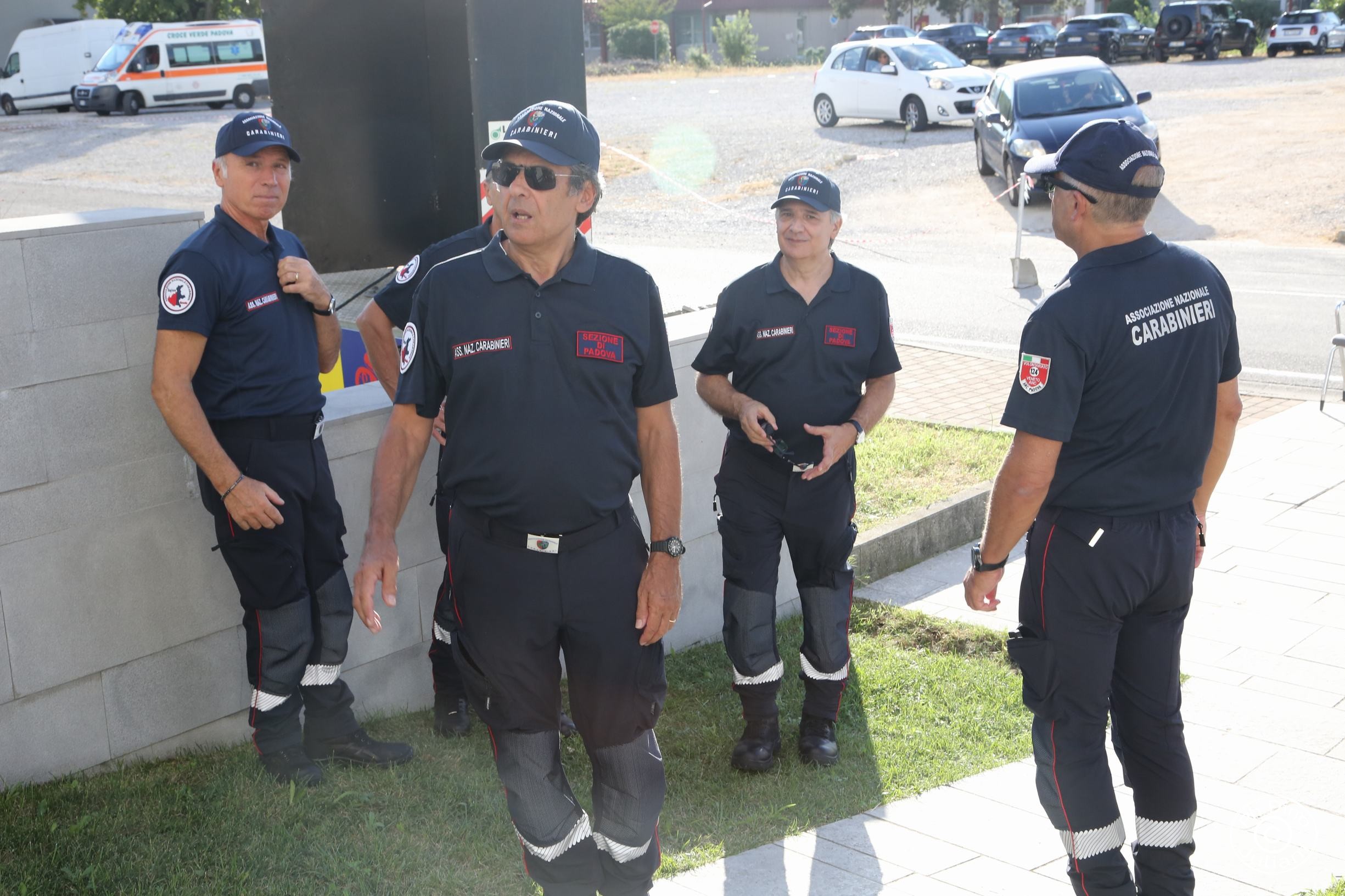 Gruppo di volontari dell’Associazione Nazionale Carabinieri in uniforme, in piedi all’esterno durante un evento.