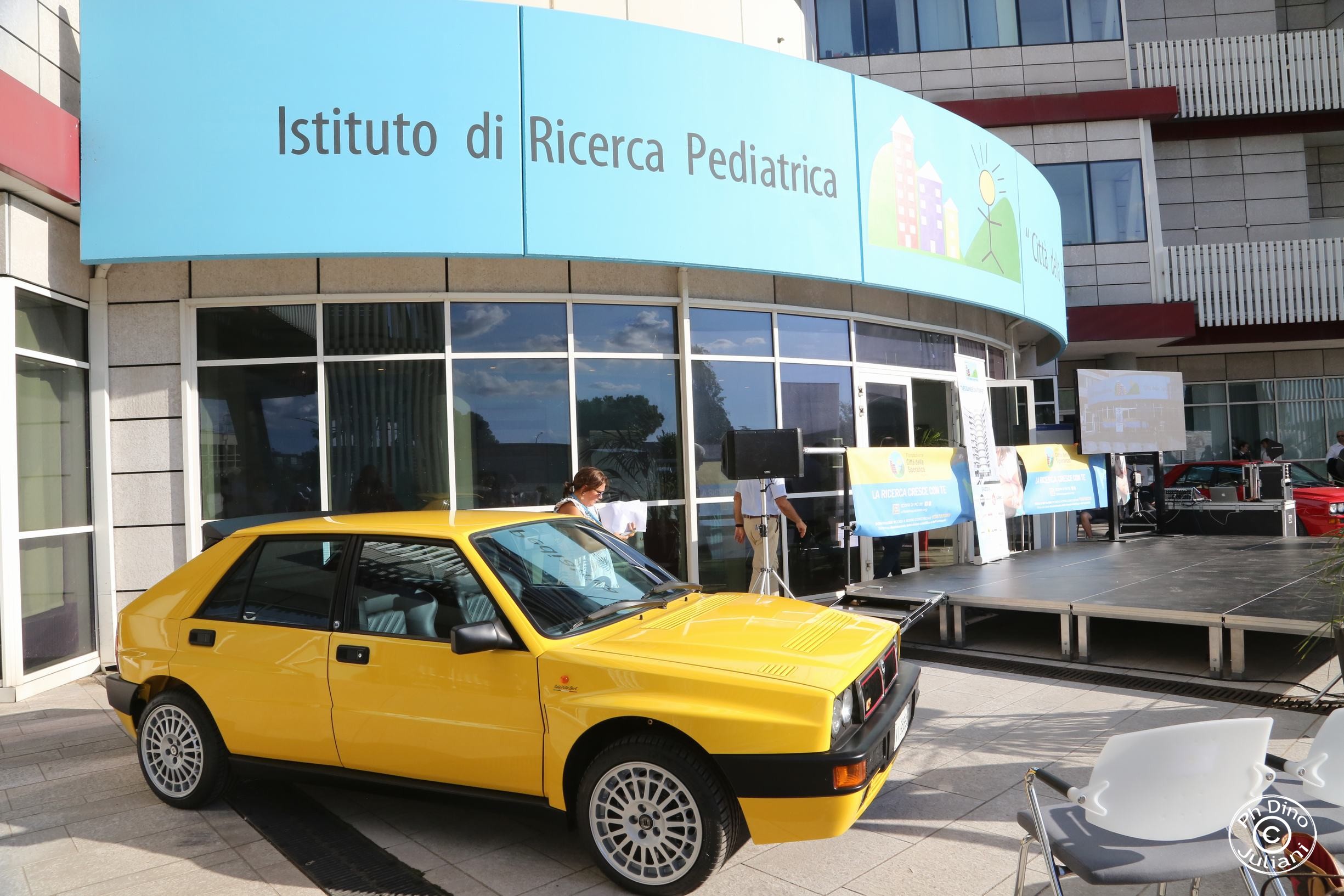 In primo piano, una vettura sportiva gialla parcheggiata vicino all’ingresso.