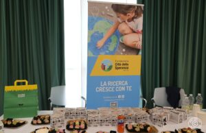 Tavolo con cibo vegano davanti a un roll-up della Fondazione Città della Speranza.