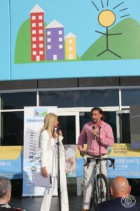 due persone sul palco davanti all'ingresso di Città della Speranza per un evento all'aperto