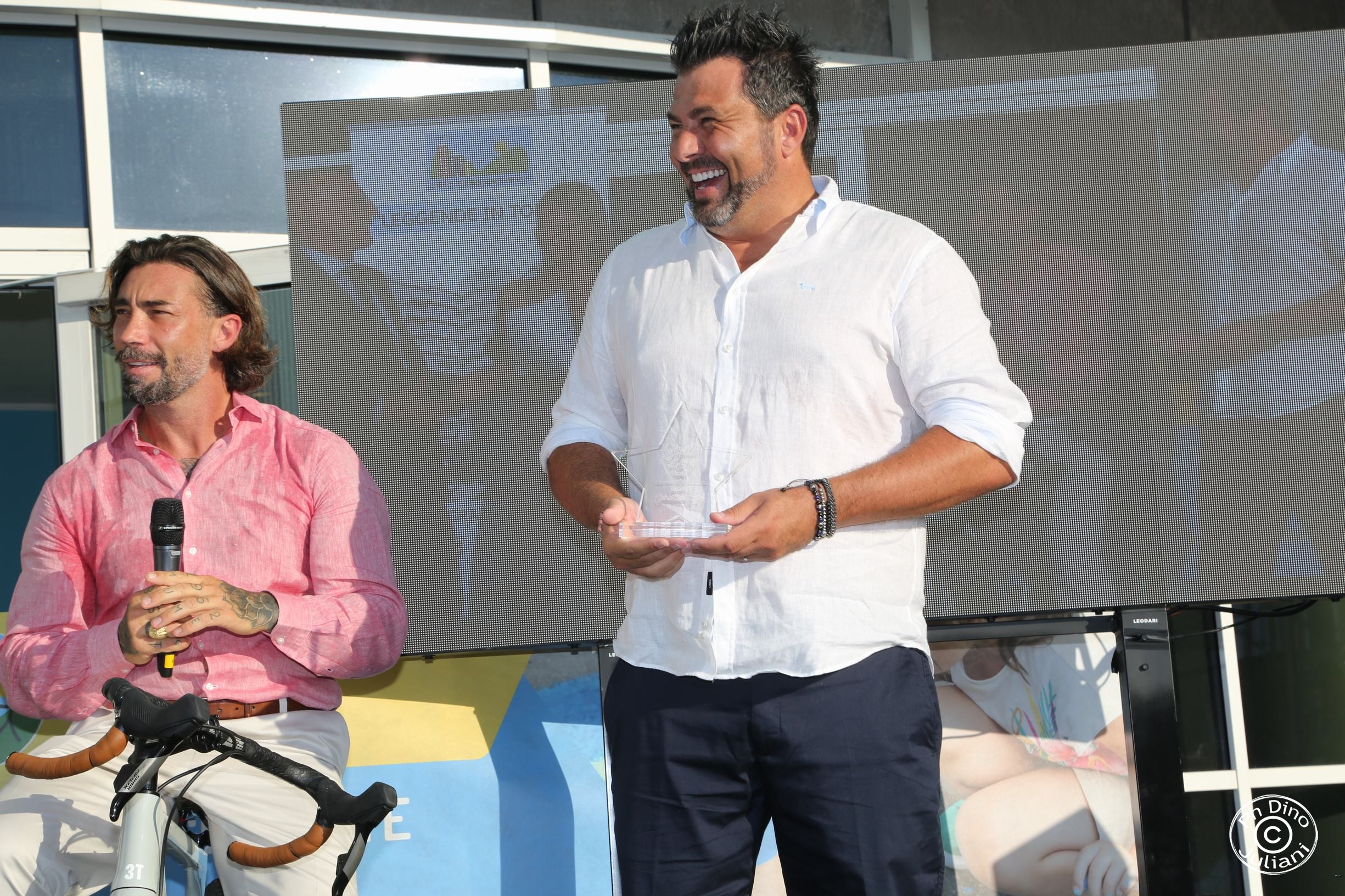 uomo sorridente in in camicia bianca che ha ricevuto un premio.