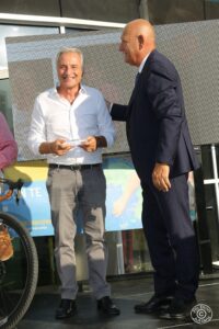 Consegna di un premio durante l’evento “Leggende in Torre”, con due persone sorridenti sul palco.