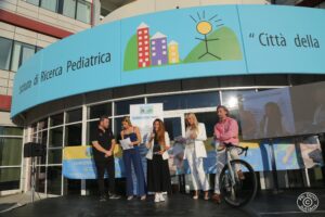 Premiazione all’evento “Leggende in Torre” della Fondazione Città della Speranza: una donna riceve un riconoscimento e parla al pubblico tenendo un microfono.