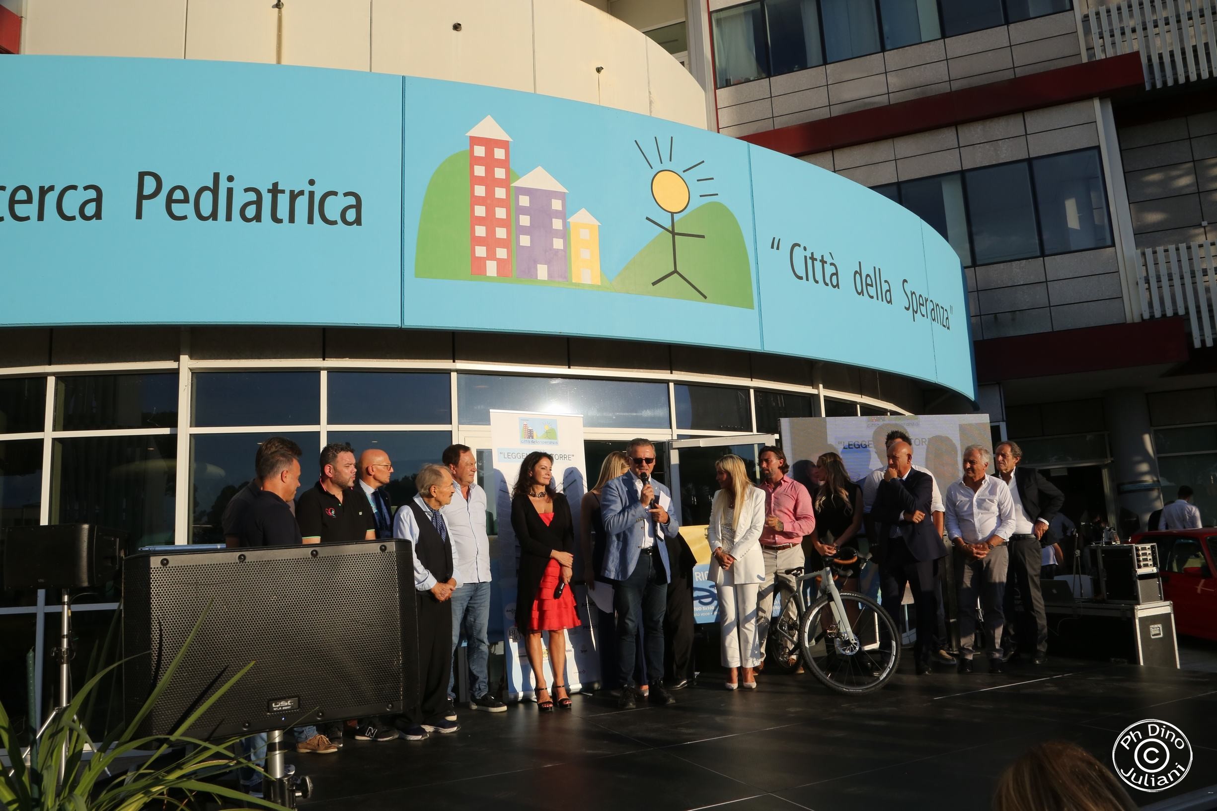 Persone sul palco davanti all'ingresso di Città della Speranza