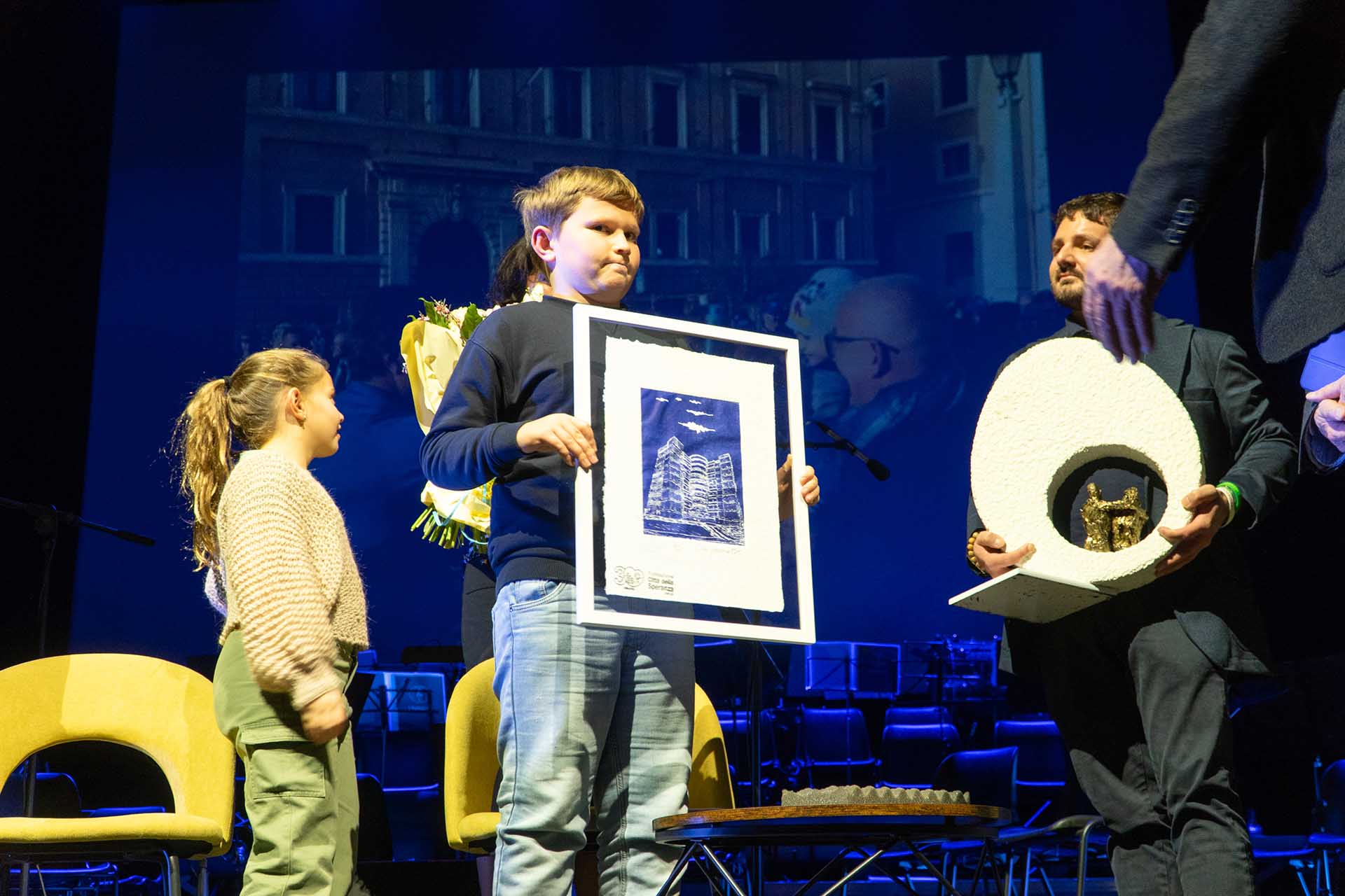 Bambino con un quadro in mano sul palco di Gran teatro Geox a Padova