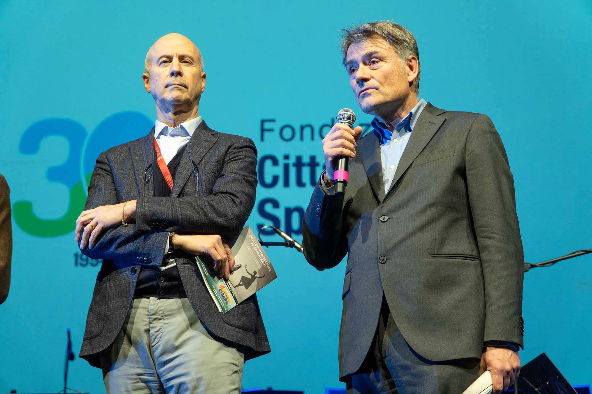 2 uomini sul palco con il microfono alla festa dell'anniversario trentennale di Città della Speranza