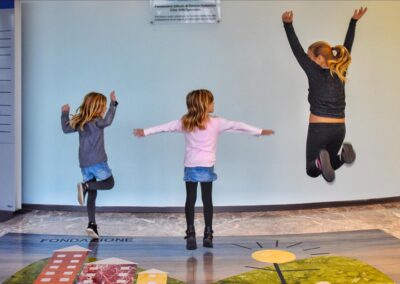 3 bambine che saltano dentro l'edificio di Città della speranza