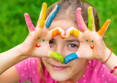 Mani colorati di una bambina che disegna un cuore